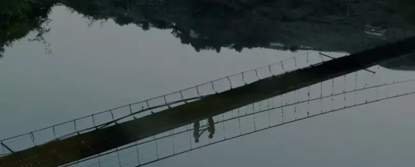 Screencap of a clip from an indigenous Taiwanese film, picturing the reflection of two people on a bridge in a body of water